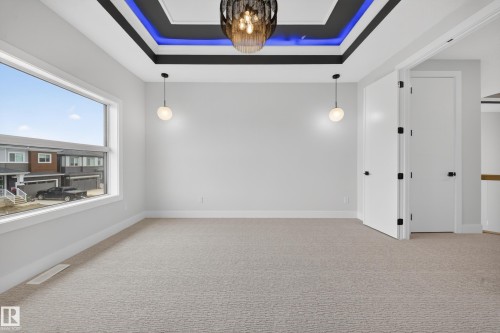 Recessed tray ceiling with accent lighting, large picture window, and neutral wall-to-wall carpeting - 8737 Mayday Lane Sw, Edmonton, AB 