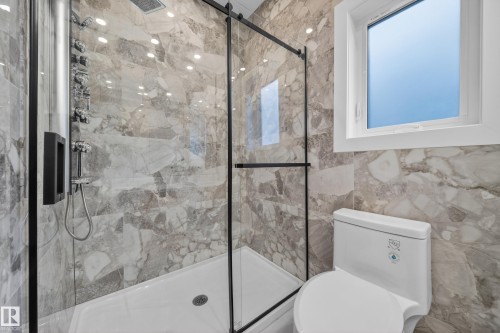 Walk-in shower with a glass enclosure, multiple shower heads, and marble-style wall tiles - 8737 Mayday Lane Sw, Edmonton, AB 
