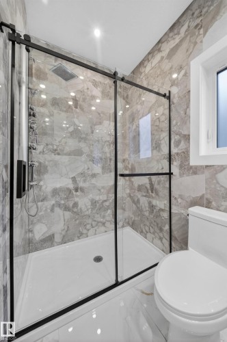Glass-enclosed shower with matte black hardware, rain shower head, and full-height stone-look tile - 8737 Mayday Lane Sw, Edmonton, AB 