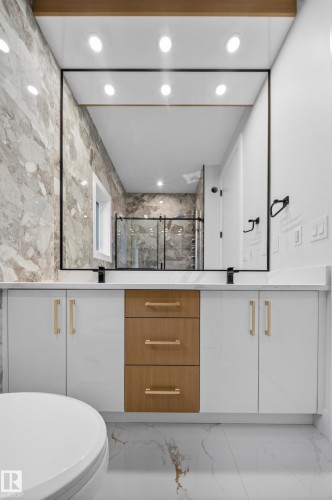 Vanity with white cabinetry and wood-finish drawers, quartz countertop, and a large wall-mounted mirror - 8737 Mayday Lane Sw, Edmonton, AB 