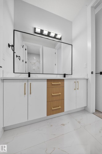 Integrated vanity with white cabinetry, wood-finish drawers, and gold-tone hardware - 8737 Mayday Lane Sw, Edmonton, AB 