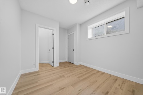 Light wood-finish flooring with white trim - 8737 Mayday Lane Sw, Edmonton, AB 