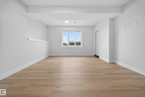 Light wood-finish flooring, white walls, recessed ceiling light, white trim, and a window with a white frame - 8737 Mayday Lane Sw, Edmonton, AB 