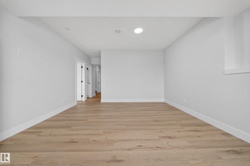 Spacious open area with wood-finish flooring, white walls, and recessed lighting - 8737 Mayday Lane Sw, Edmonton, AB 