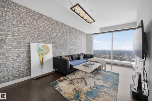Exposed brick accent wall, expansive floor-to-ceiling windows, dark wood-finish flooring, and a rectangular ceiling light fixture - #4007 10360 102 St Nw, Edmonton, AB 