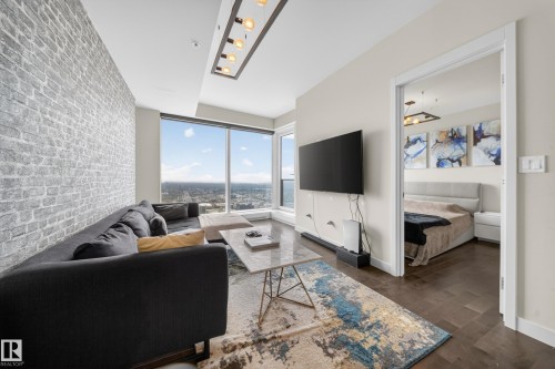 Expansive windows with city scenery, a unique brick-finish accent wall, and wood-finish flooring - #4007 10360 102 St Nw, Edmonton, AB 
