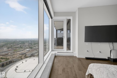Floor-to-ceiling windows, wood-finish flooring, white trim, light gray walls, and a glass-paneled door - #4007 10360 102 St Nw, Edmonton, AB 