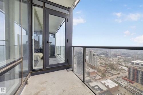 Balcony with concrete flooring and a glass railing, featuring a cityscape in the background - #4007 10360 102 St Nw, Edmonton, AB 