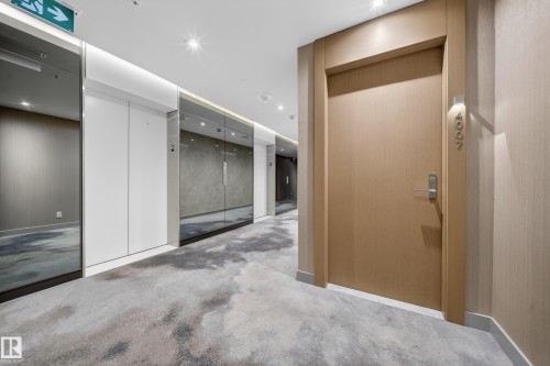 Textured wall covering, recessed lighting, wood-finish entryway door, modern lever handle, and patterned carpeting - #4007 10360 102 St Nw, Edmonton, AB 