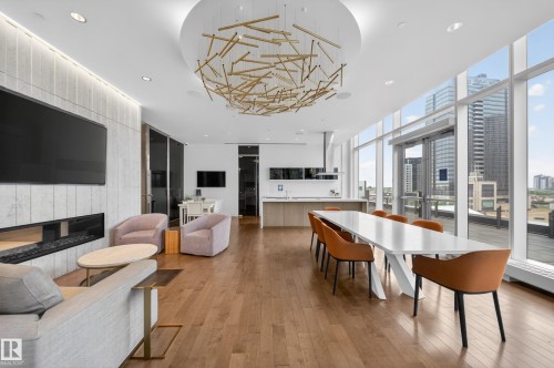Floor-to-ceiling windows, wood-finish flooring, a contemporary linear fireplace, and a built-in kitchen island with integrated appliances - #4007 10360 102 St Nw, Edmonton, AB 