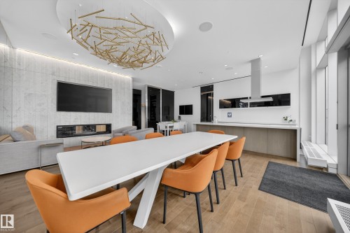 Open-concept living space featuring wood-finish flooring, a linear fireplace, and a contemporary chandelier - #4007 10360 102 St Nw, Edmonton, AB 