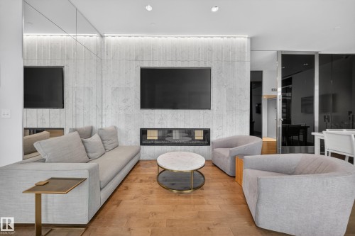 Wood-finish flooring, integrated linear fireplace, textured stone wall, built-in display niches, and recessed lighting - #4007 10360 102 St Nw, Edmonton, AB 