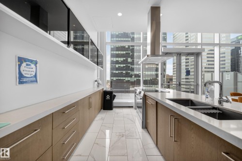 Modern kitchen featuring light wood-finish cabinetry, white countertops, and a double stainless steel sink - #4007 10360 102 St Nw, Edmonton, AB 