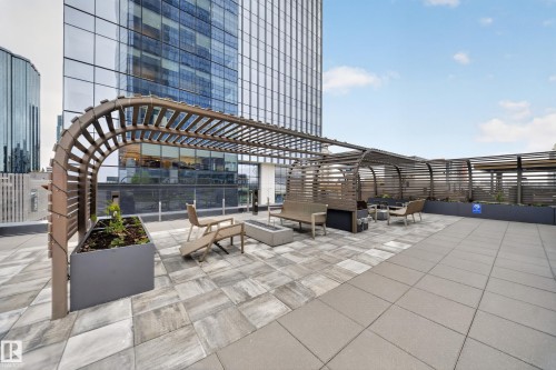 Expansive rooftop patio featuring a large pergola, paver flooring, built-in planters, and a fire pit - #4007 10360 102 St Nw, Edmonton, AB 
