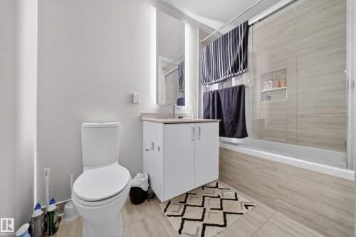 White cabinet vanity with a light-toned countertop, illuminated mirror, and a built-in shower niche - #4007 10360 102 St Nw, Edmonton, AB 