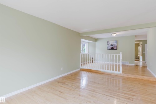 Open-concept living area featuring light wood-finish flooring, light green painted walls, and white trim - 2439 112 Street Nw, Edmonton, AB - Indoor