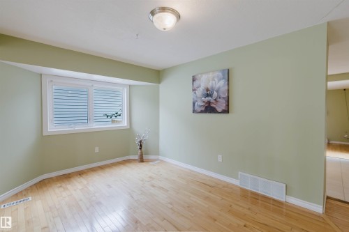 Hardwood flooring throughout a room with light green walls and white baseboards - 2439 112 Street Nw, Edmonton, AB - Indoor Photo Showing Other Room