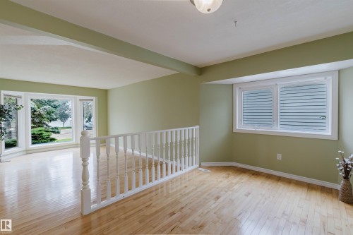 Hardwood flooring throughout a spacious room with light green walls - 2439 112 Street Nw, Edmonton, AB - Indoor Photo Showing Other Room