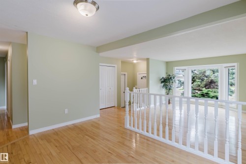 Hardwood flooring extends throughout this interior space, complemented by light green wall finishes - 2439 112 Street Nw, Edmonton, AB - Indoor Photo Showing Other Room