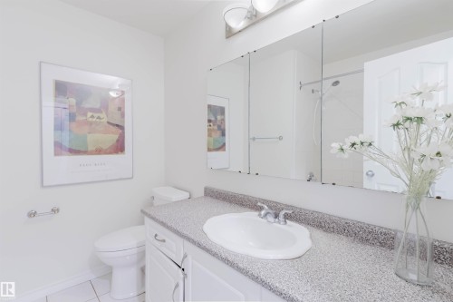 Bathroom vanity with an integrated sink, speckled countertop, and white cabinetry - 2439 112 Street Nw, Edmonton, AB - Indoor Photo Showing Bathroom