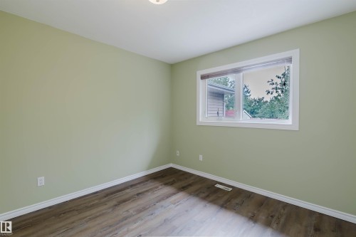 Room featuring wood-finish flooring, a contemporary window, and soft green walls with crisp white trim - 2439 112 Street Nw, Edmonton, AB - Indoor Photo Showing Other Room