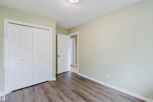 Interior room featuring wood-finish flooring, light green painted walls, white baseboards, and a semi-flush mount ceiling light - 2439 112 Street Nw, Edmonton, AB - Indoor Photo Showing Other Room