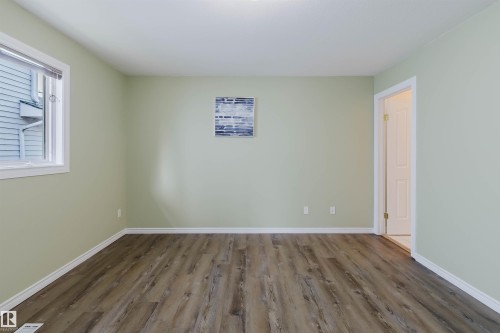Interior space featuring wood-finish flooring, light green walls, white baseboards, and a white ceiling - 2439 112 Street Nw, Edmonton, AB - Indoor Photo Showing Other Room