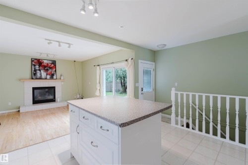 Central island with a speckled countertop and storage drawers, contrasting with light tile flooring - 2439 112 Street Nw, Edmonton, AB - Indoor With Fireplace