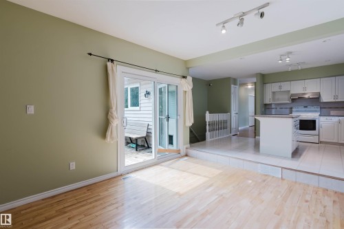 Hardwood-finish flooring in the living area with sliding glass doors leading to an outdoor space - 2439 112 Street Nw, Edmonton, AB - Indoor Photo Showing Kitchen