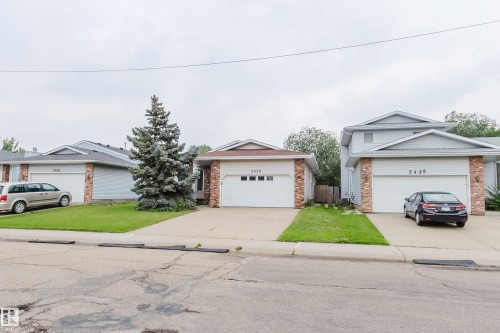 Exterior featuring a single-car garage, light-colored siding, and brick accents - 2439 112 Street Nw, Edmonton, AB - Outdoor With Facade