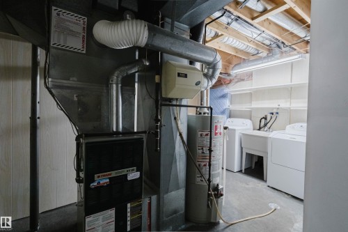 Dedicated utility area featuring a furnace, water heater, washing machine, clothes dryer, and laundry sink - 2439 112 Street Nw, Edmonton, AB - Indoor Photo Showing Laundry Room