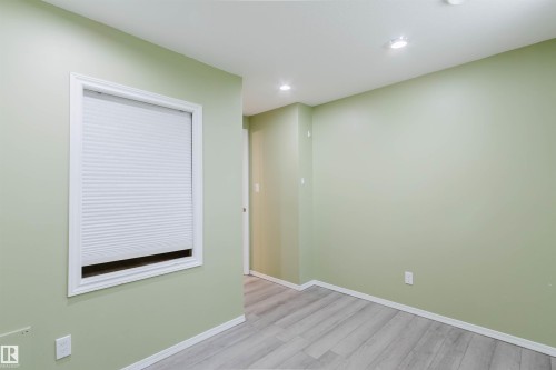 Interior room featuring light green walls, light wood-finish flooring, recessed lighting, and a window with a cellular shade - 2439 112 Street Nw, Edmonton, AB - Indoor Photo Showing Other Room