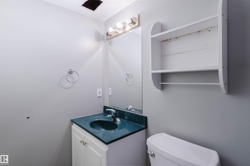 Bathroom vanity featuring a dark countertop with an integrated sink, chrome faucet, and white cabinetry - 2439 112 Street Nw, Edmonton, AB - Indoor Photo Showing Bathroom