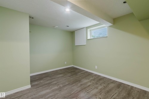 Versatile room featuring light green walls, wood-finish flooring, recessed lighting, and a window with horizontal blinds - 2439 112 Street Nw, Edmonton, AB - Indoor