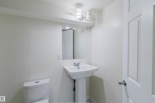 Pedestal sink with chrome faucet, mirror, and contemporary vanity lighting - 2439 112 Street Nw, Edmonton, AB - Indoor Photo Showing Bathroom