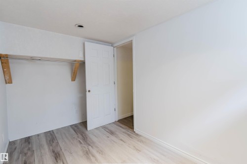 Bedroom featuring wood-finish flooring, a built-in closet rod, recessed ceiling lighting, and a paneled interior door - 2439 112 Street Nw, Edmonton, AB - Indoor Photo Showing Other Room