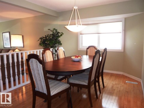 Dining area featuring wood-finish flooring, a window with roller shades, and a ceiling-mounted light fixture - 2439 112 Street Nw, Edmonton, AB - Indoor Photo Showing Dining Room