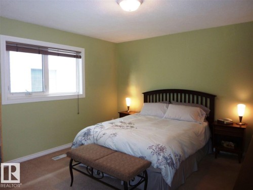 Bedroom featuring a white framed window with integrated blinds, light green painted walls, and neutral carpeting - 2439 112 Street Nw, Edmonton, AB - Indoor Photo Showing Bedroom