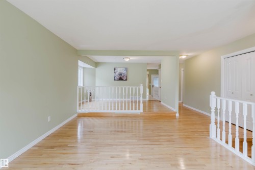 Open concept living area featuring light wood-finish flooring, a white spindle railing, and light green walls - 2439 112 Street Nw, Edmonton, AB - Indoor Photo Showing Other Room