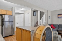 Kitchen with stainless steel refrigerator, wood-finish flooring, and a kitchen island with storage - 