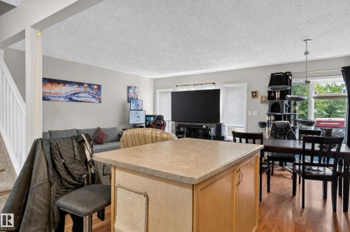 Open-concept living space featuring wood-finish flooring and a kitchen island with a light-toned countertop - 21312 48 Avenue Nw, Edmonton, AB 