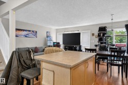Open-concept living space featuring wood-finish flooring and a kitchen island with a light-toned countertop - 