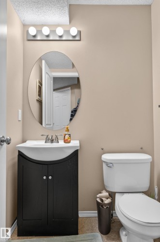 Built-in vanity with dark wood-finish cabinetry, integrated sink, and chrome faucet - 21312 48 Avenue Nw, Edmonton, AB 