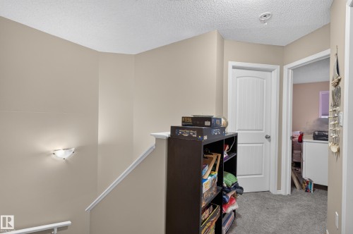 Neutral wall color, wall-mounted light fixture, white interior door, carpeted flooring, and a ceiling light fixture - 21312 48 Avenue Nw, Edmonton, AB 