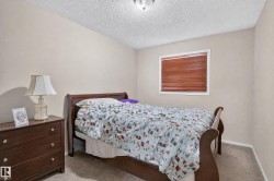 Comfortable secondary bedroom featuring carpeted flooring, wood-finish furnishings, and soft ambient lighting from a table lamp - 