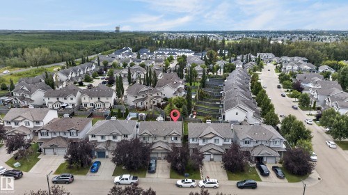 Aerial view of an established residential community featuring tree-lined streets, mature landscaping with cypress and deciduous trees, and a collection of multi-story homes with varied architectural styles and neutral-toned exteriors - 21312 48 Avenue Nw, Edmonton, AB 