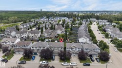 Aerial view of an established residential community featuring tree-lined streets, mature landscaping with cypress and deciduous trees, and a collection of multi-story homes with varied architectural styles and neutral-toned exteriors - 