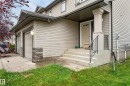 Beige siding exterior with stone accent columns, two-car garage, and concrete steps with a black metal handrail - 21312 48 Avenue Nw, Edmonton, AB 