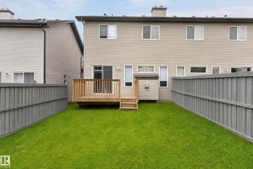 Rear exterior featuring a wooden deck, slatted privacy fencing, and a manicured lawn - 21312 48 Avenue Nw, Edmonton, AB 