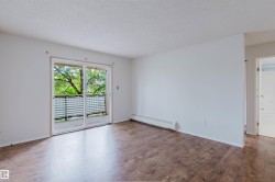 Wood-finish flooring, white walls, and sliding glass doors opening to a balcony with metal railings - 